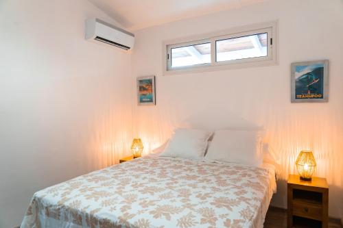 a white bedroom with a bed and two lamps at Le Rêve Tropical proximité plage et commerces in Punaauia