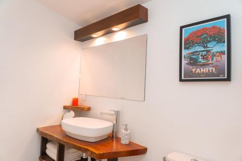 ein Bad mit einem Waschbecken und einem Spiegel in der Unterkunft Le Rêve Tropical proximité plage et commerces in Punaauia