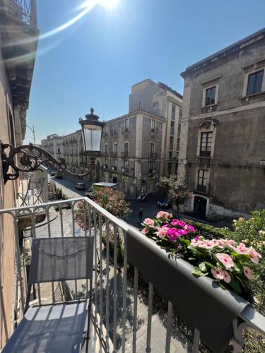 a balcony with flowers and a chair on a city street at San Giuliano Palace in Catania