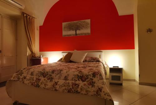 a bedroom with a large bed with a red wall at Casa San Brasi di Mariano e Lucia in Acireale