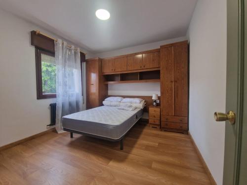 a bedroom with a bed and wooden cabinets and a window at Apartamento céntrico Llanes in Llanes