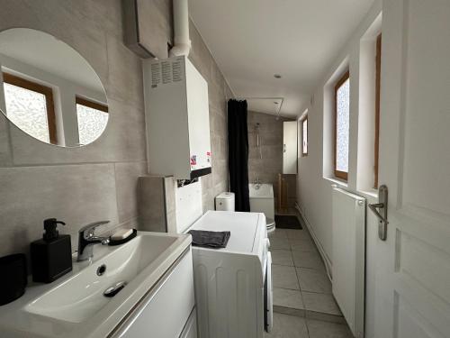 La salle de bains blanche est pourvue d'un lavabo et d'un miroir. dans l'établissement Maison Lilloise 3 chambres, à Lille