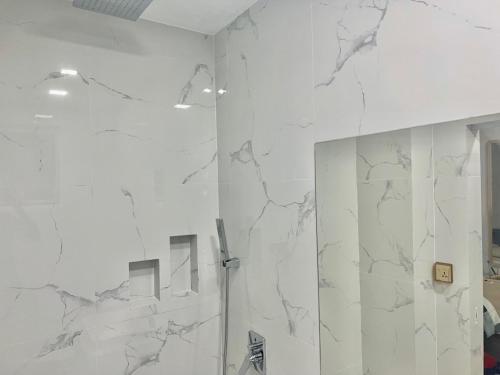 a white bathroom with a mirror and a shower at Dhonveli Stay in Hulhumale