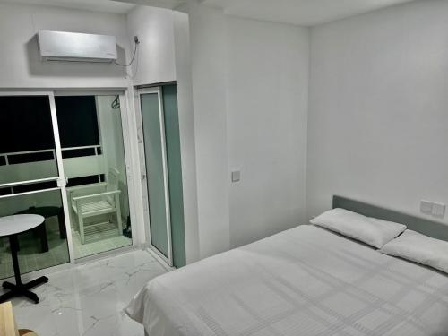 a white bedroom with a bed and a window at Dhonveli Stay in Hulhumale