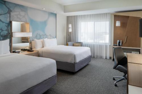 a hotel room with two beds and a desk at Courtyard by Marriott Houston Northwest/Cypress in Cypress