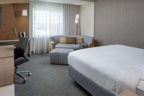 a hotel room with a bed and a chair at Courtyard by Marriott Houston Northwest/Cypress in Cypress