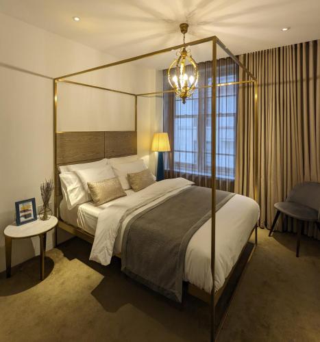 a bedroom with a canopy bed and a chandelier at Soho West End in London