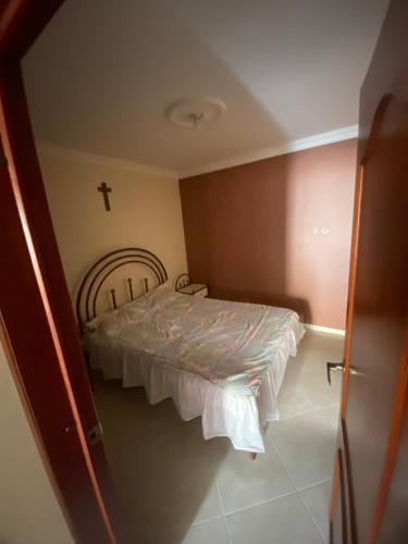 a small bedroom with a bed with a cross on the wall at Habitación en Junin 2 Piedecuesta in Piedecuesta