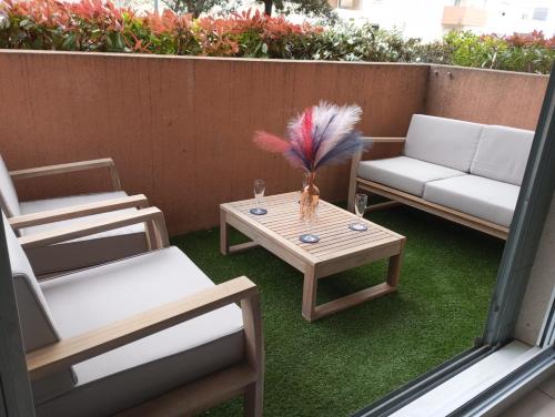 a patio with chairs and a table with a vase on it at L'Étoile Biterroise - Appartement de Vacances avec Piscine et Parking gratuit à Béziers in Béziers