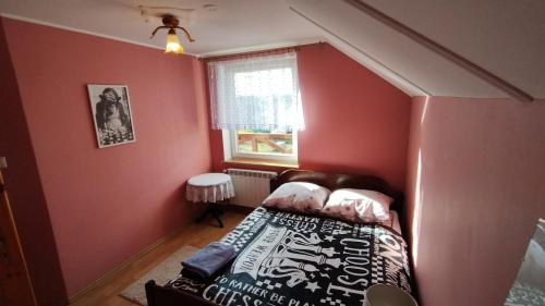 a small room with a bed and a window at Chess Apartament in Augustów
