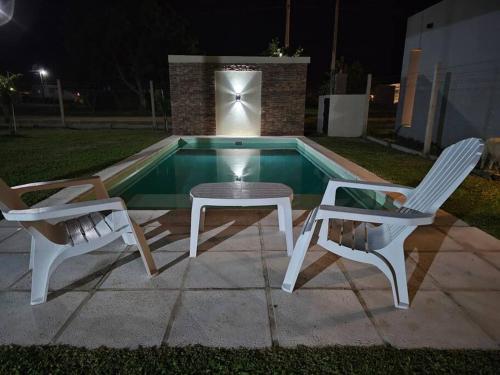 twee stoelen en een tafel naast een zwembad in de nacht bij Casa quinta Gabi in San José del Rincón