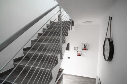 un escalier dans une chambre blanche avec une horloge sur le mur dans l'établissement Dolce Lago B&B, à Calolziocorte