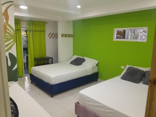 2 camas en una habitación con paredes verdes en Hostal Alto de la Montaña, en Minca