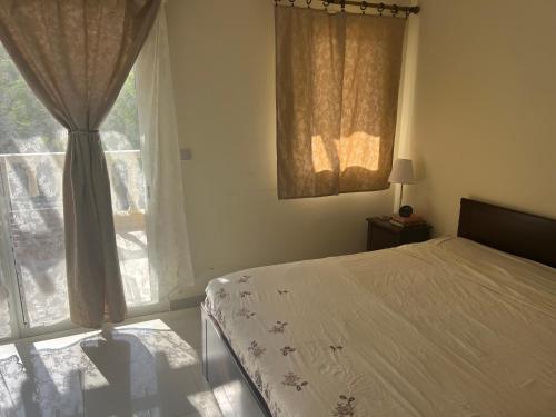 a bedroom with a bed and a large window at Cozy Villa with Pool Access in Ras al Khaimah