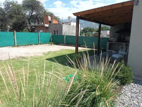 a backyard with a green fence and grass at La Justina - Alquiler Temporario in Cafayate
