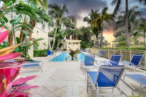 a resort pool with blue chairs and palm trees at Hilton Garden Inn Palm Beach Gardens in Palm Beach Gardens