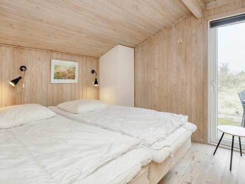 a bedroom with a large white bed in a wooden wall at 9 person holiday home in Blokhus-By Traum in Blokhus