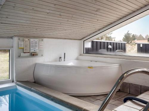 a white tub sitting in a bathroom with a window at 9 person holiday home in Blokhus-By Traum in Blokhus