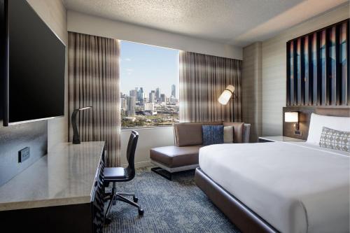 ダラスにあるRenaissance Dallas Hotelのベッド、デスク、窓が備わるホテルルームです。