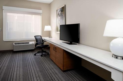 a hotel room with a desk with a television and a window at Hilton Garden Inn Roseville in Roseville