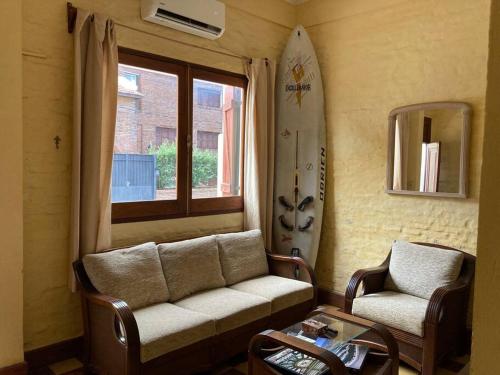 een woonkamer met een bank en een surfplank bij La casita de Morgan in Mercedes