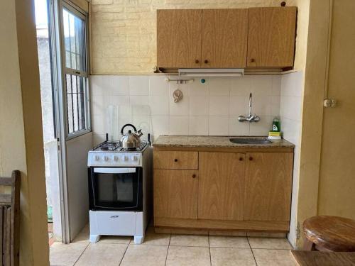 uma pequena cozinha com um fogão e um lavatório em La casita de Morgan em Mercedes
