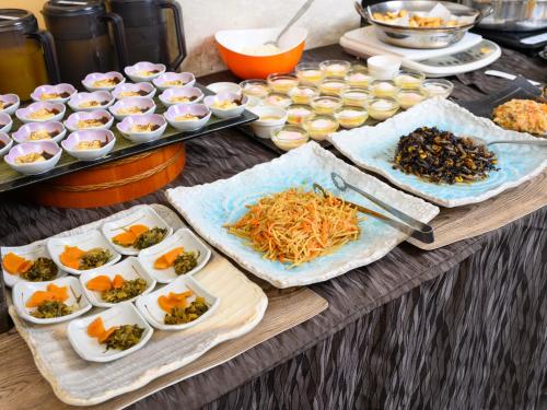 einen Tisch mit Teller mit Lebensmitteln und Schüsseln mit Lebensmitteln in der Unterkunft Iga Ueno City Hotel in Iga