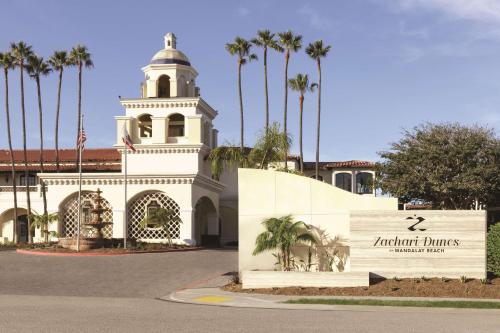 a building with a clock tower and a sign in front at Zachari Dunes on Mandalay Beach, Curio Collection by Hilton in Oxnard