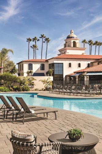 a resort with a pool and chairs and a building at Zachari Dunes on Mandalay Beach, Curio Collection by Hilton in Oxnard