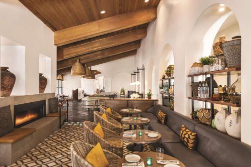 a restaurant with tables and chairs and a fireplace at Zachari Dunes on Mandalay Beach, Curio Collection by Hilton in Oxnard