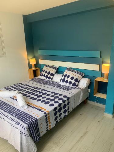 a bedroom with a blue and white bed with pillows at Rez de jardin Ylang Ylang in Saint-François