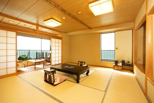 a room with a table and chairs in a room with windows at Ako Onsen Shokichi in Ako