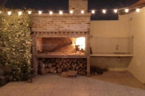 a room with a fireplace with a pile of logs at CCasa con piscina para 8 personas in Mercedes