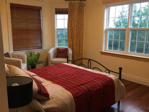 a bedroom with a bed and two chairs and windows at Beautiful and Peaceful Home in Halifax