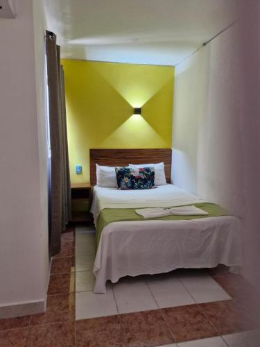 a bedroom with a bed with a yellow wall at Hotel Capri Playa a una calle de la Playa Regatas in Veracruz
