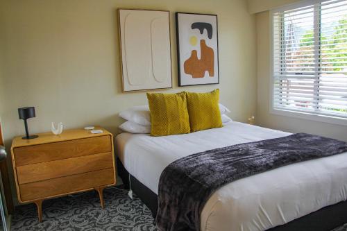 a bedroom with two beds and a dresser and a window at Arrowtown Motel in Arrowtown