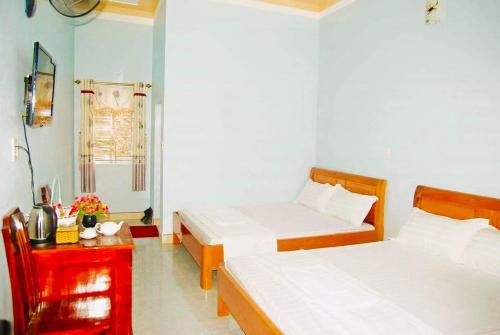 a room with two beds and a red table at Nhà nghỉ Thiên Phúc in Mộc Châu