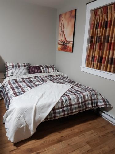 una camera da letto con un letto con una coperta scozzese e una finestra di East End Suite a Eastern Passage