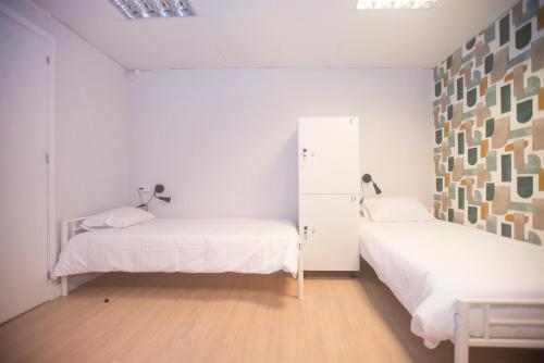 two beds in a room with white walls and wooden floors at Aerostay Hostel in Moreira