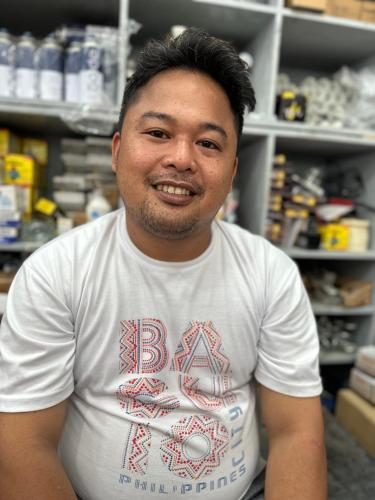 Een man met een wit shirt in een winkel. bij Ryan house pf serv in Manilla