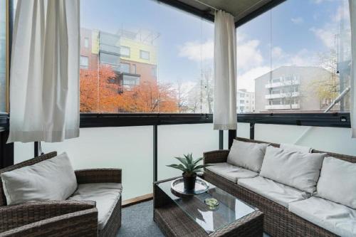 a living room with a couch and a table and large windows at City flat with a sauna & balcony in Helsinki