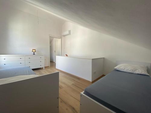a white bedroom with two beds and a dresser at Apartments by the sea Brgulje, Molat - 22856 in Brgulje