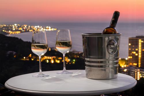 two glasses of wine on a table with a bottle of wine at Rhodes Skyline Suite with In Door Jacuzzi Sea View in Ixia