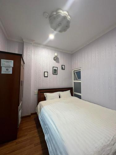 a bedroom with a large white bed and a light at Hotel Đăng Uyên D65 in Da Lat