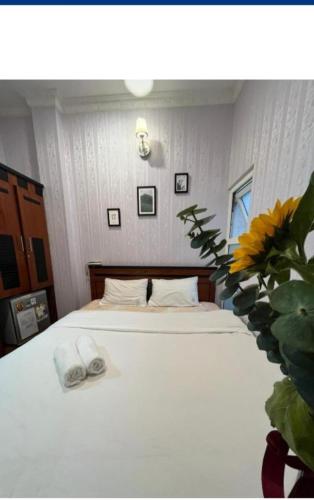a bedroom with a white bed with a pair of slippers at Hotel Đăng Uyên D65 in Da Lat