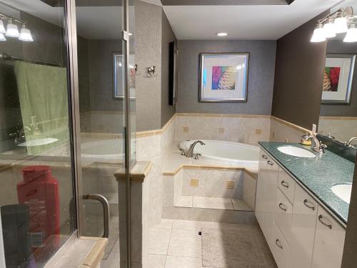 Un baño con dos lavabos, una bañera y una ducha. en Ponce Inlet Florida Breathtaking Oceanfront Penthouse Villa!, en Ponce Inlet