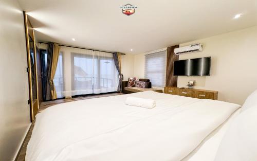 - une chambre avec un grand lit blanc et une télévision à écran plat dans l'établissement Oceanview Cabins, à Nyanyanu