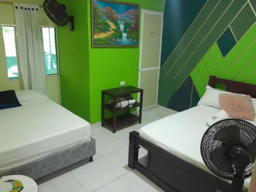 a bedroom with two beds and a green wall at Hostal Alto de la Montaña in Minca