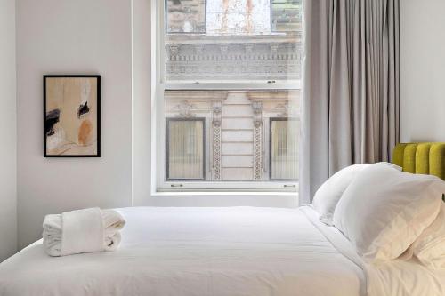 a bedroom with a white bed and a window at The Nomad Saint Jacques in Montréal