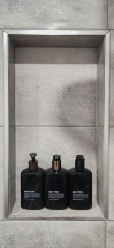 three black containers sitting on a shelf in a wall at Glossy Black Cabin in Parndana